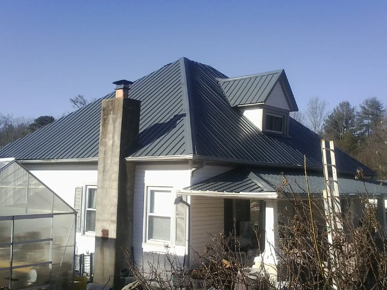 Dark blue standing seam metal roof on a white farmhouse with dormer — Slate & Tile Roof Repair by Roofing Brothers in Dudley
