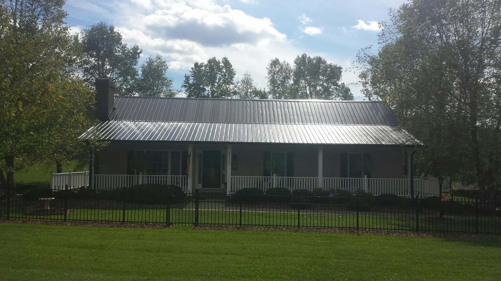 Gray metal roof on a brick ranch with a full width front porch — Gutter Guard Installation work by our crew in Dudley